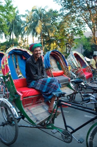 Rickshaws line the streets of Dhaka waiting for the post-office crowd. Amidst the rush and the orchestra of city sounds is a radiant smile as bright and shiny as the colors of Bangladesh.
